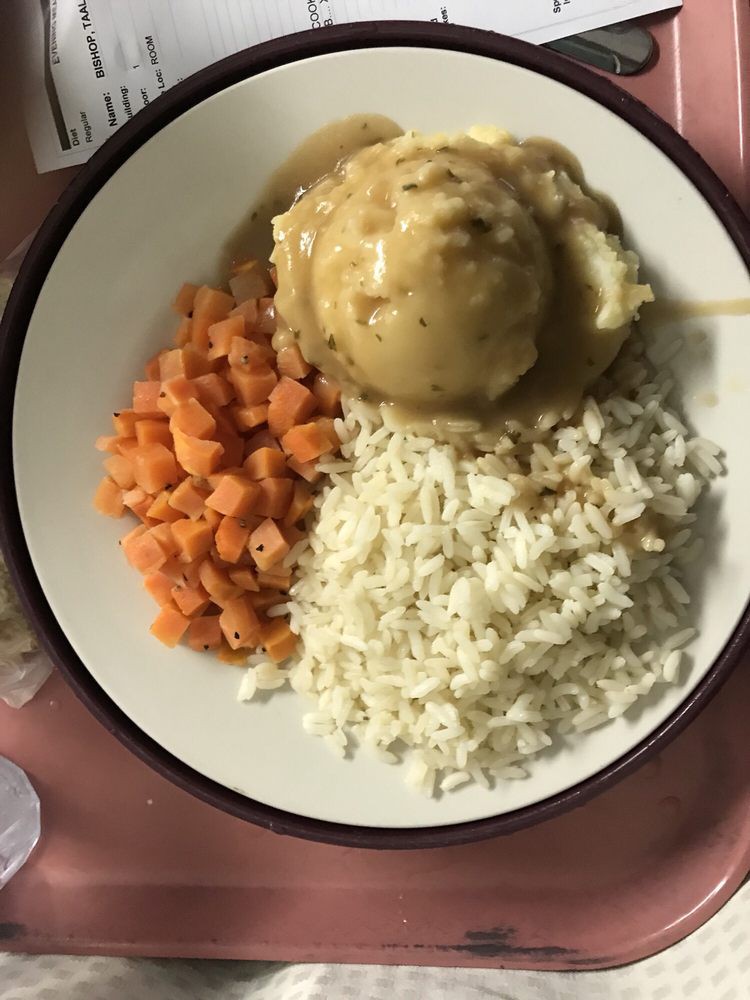 A plate of chicken with gravy, rice, and carrots.