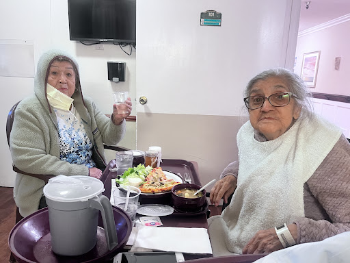 Two elderly women enjoying a meal together in a cozy setting.