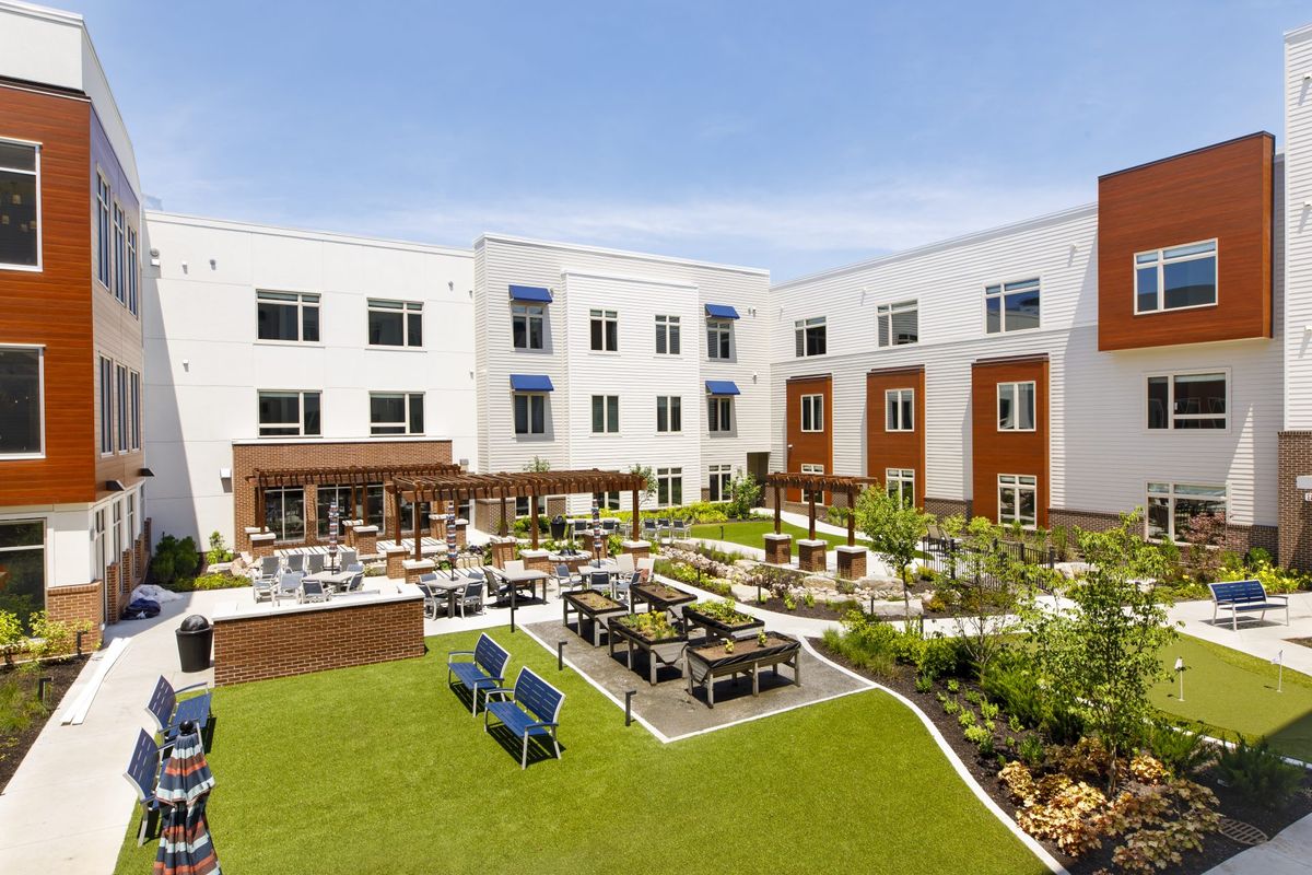 A modern building with a landscaped courtyard featuring outdoor seating and gardens.