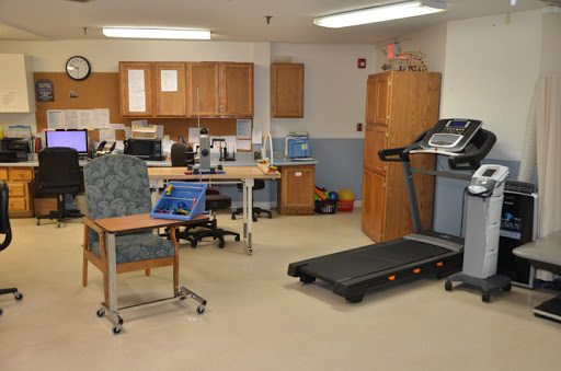 A physical therapy room equipped with a treadmill and various office furniture for rehabilitation activities.