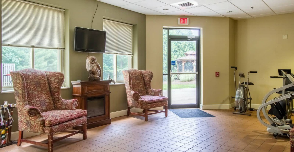 An interior view of a waiting room with chairs, a television, and an exit door.