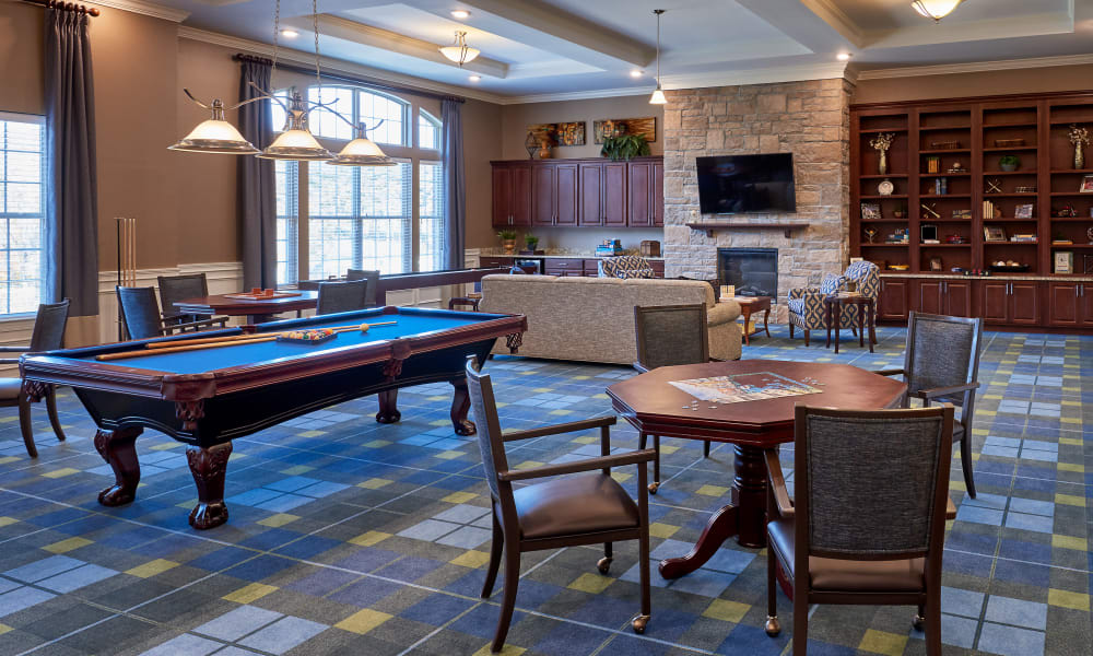A cozy recreational space featuring a pool table, seating area, and a fireplace with a TV above.