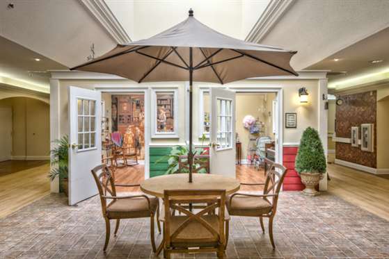 An inviting indoor patio setup with a table, chairs, and a large umbrella, surrounded by open doors leading to a cozy interior space.