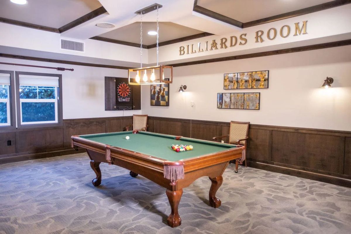 A well-decorated billiards room featuring a classic pool table under elegant lighting.