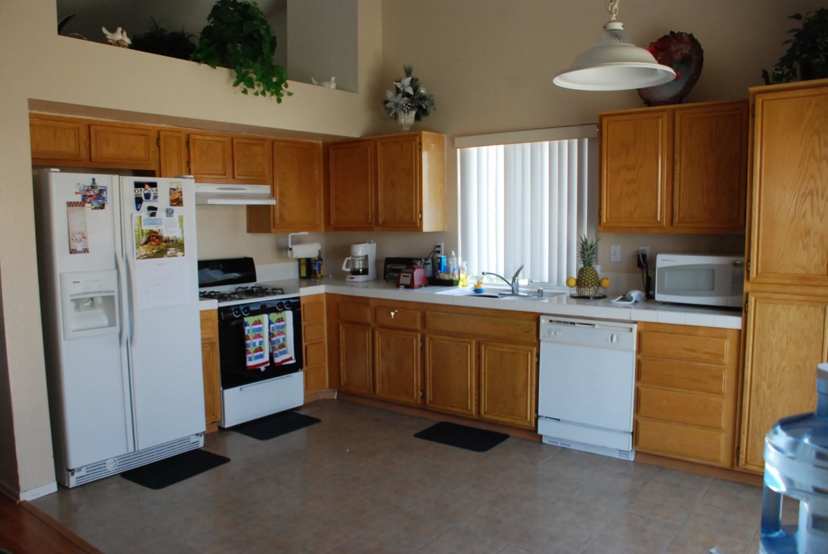 A spacious kitchen with wooden cabinets, equipped with modern appliances including a stove, refrigerator, microwave, and dishwasher.