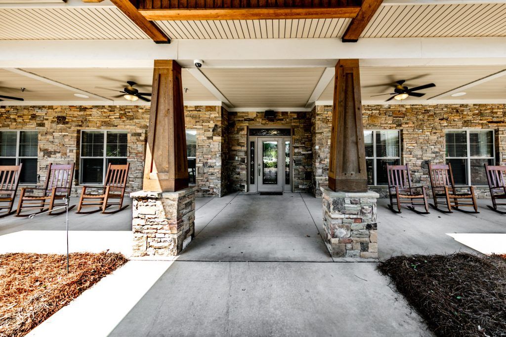 A welcoming front porch with stone pillars and rocking chairs.