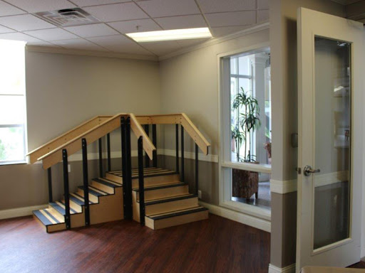 A view of an office interior featuring a staircase and a window with greenery.