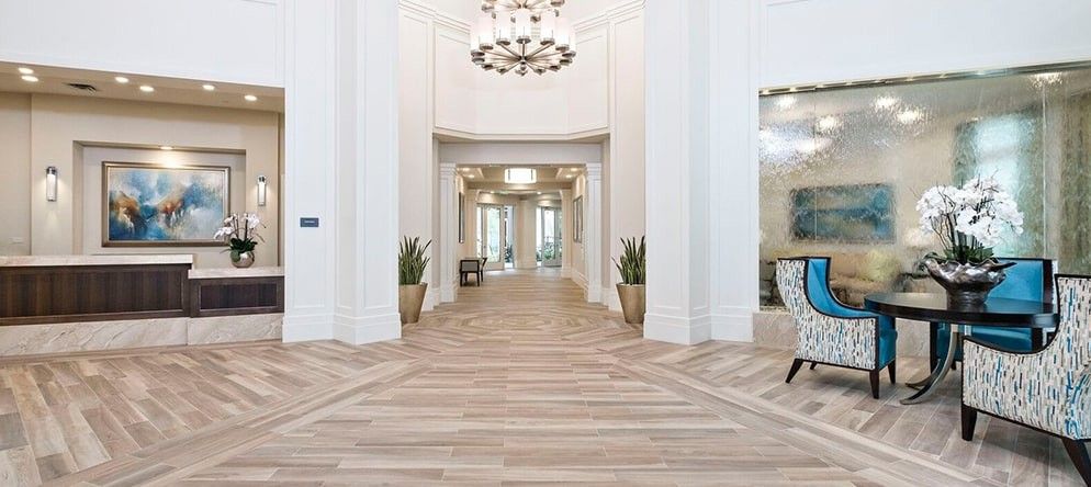 A spacious and elegant lobby with modern wooden flooring and decorative chandeliers.