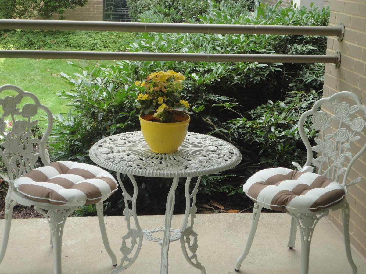 A cozy outdoor patio set with a table, two chairs, and a potted plant.