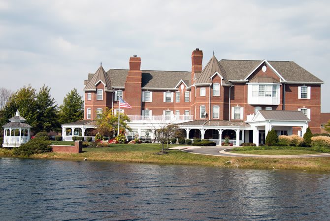 A large brick mansion situated by the waterfront on a clear day.