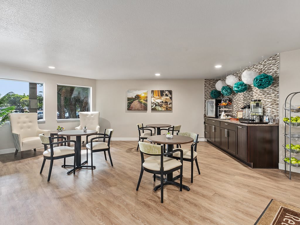 A cozy dining area with several tables and chairs, featuring tasteful decorations and a hardwood floor.