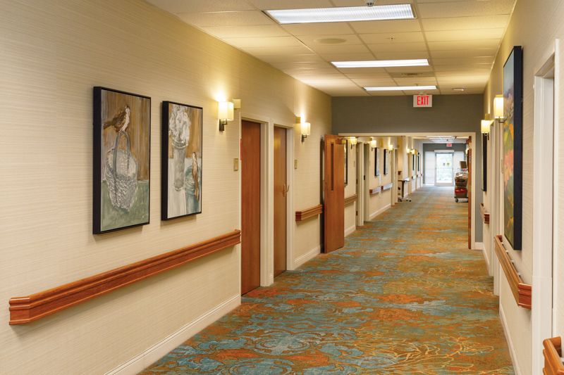 A well-lit hallway with doors on either side and artwork on the walls.