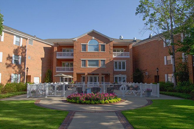 A brick apartment building with balconies and well-maintained landscaping.