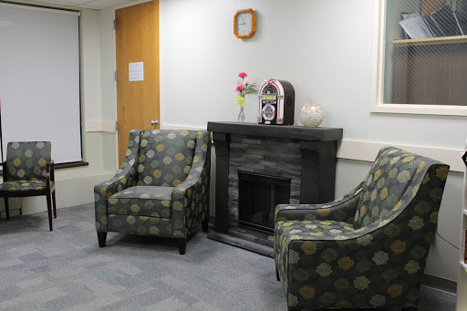 A cozy waiting area featuring patterned chairs and a decorative fireplace.