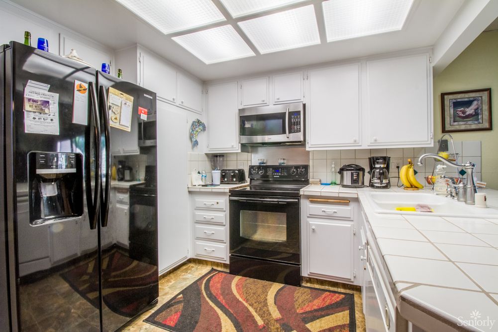 Modern kitchen with sleek appliances and a vibrant rug.