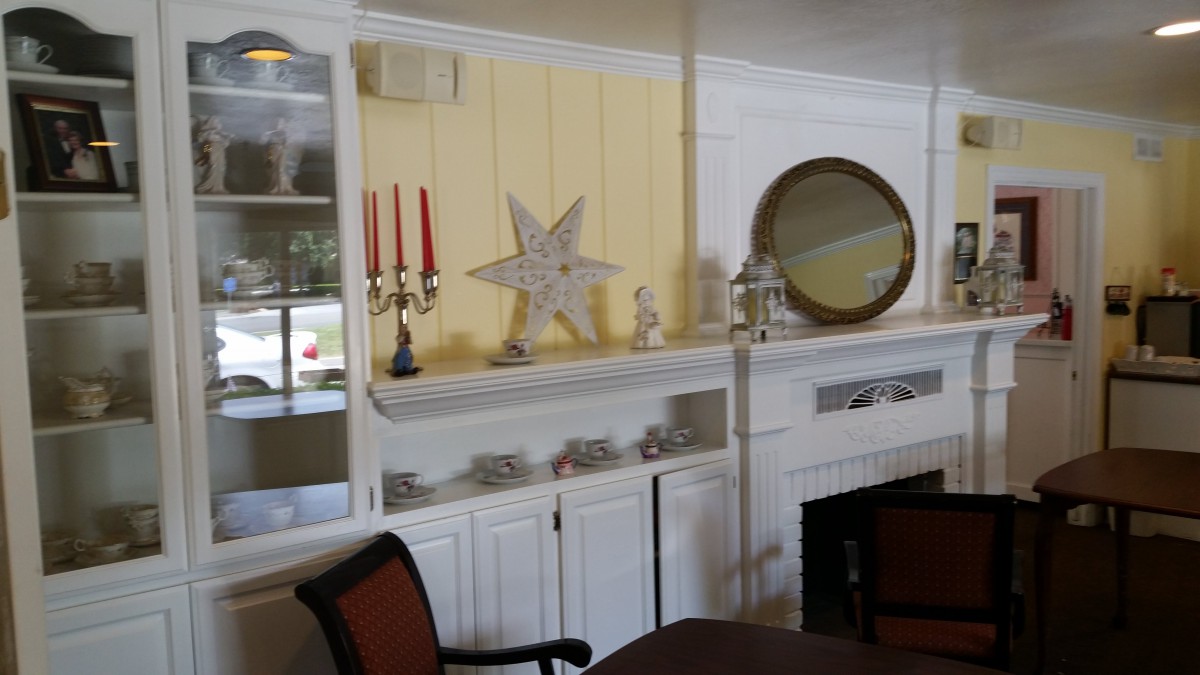 A cozy interior featuring a decorated fireplace with candles, a star ornament, and a round mirror.
