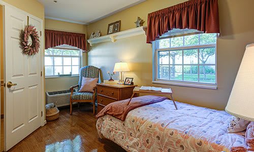 A cozy bedroom with a single bed, side table, and large windows.