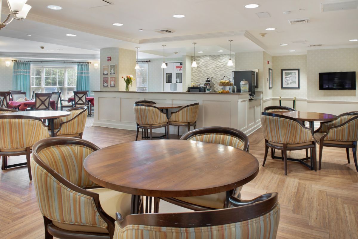A modern cafe interior with wooden tables and upholstered chairs.
