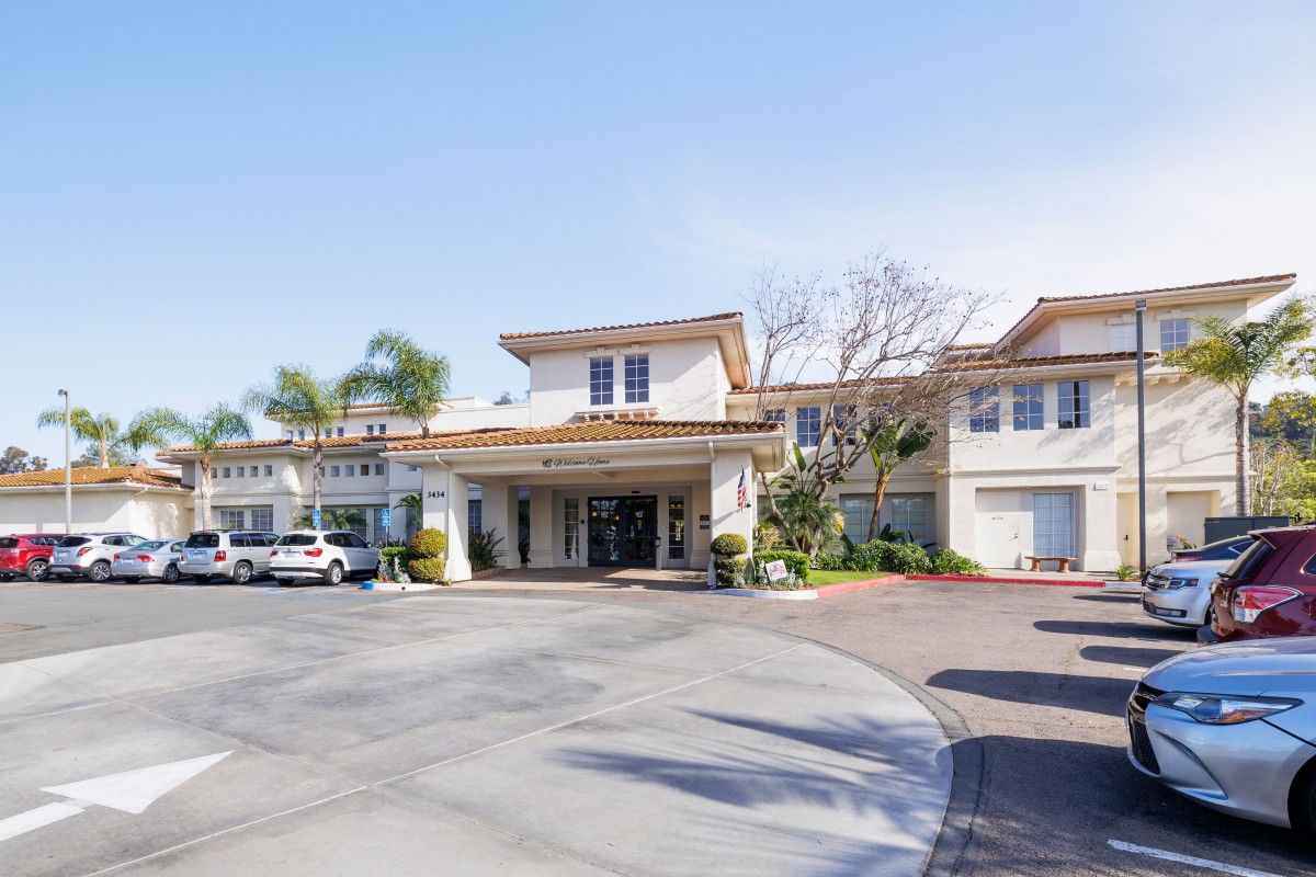 Exterior view of a hotel entrance with surrounding parking area.