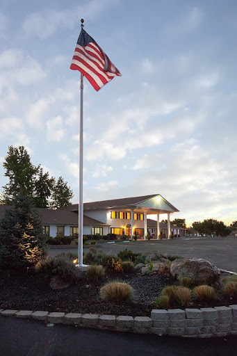 A welcoming building with an American flag flying in front, surrounded by trees and a clear sky.
