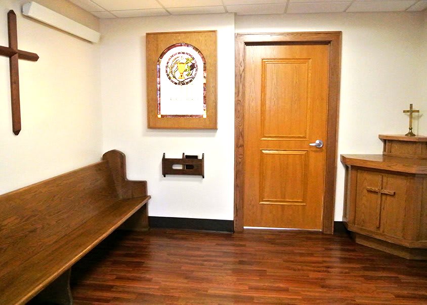 A waiting area with a wooden bench and door, featuring artwork on the wall.