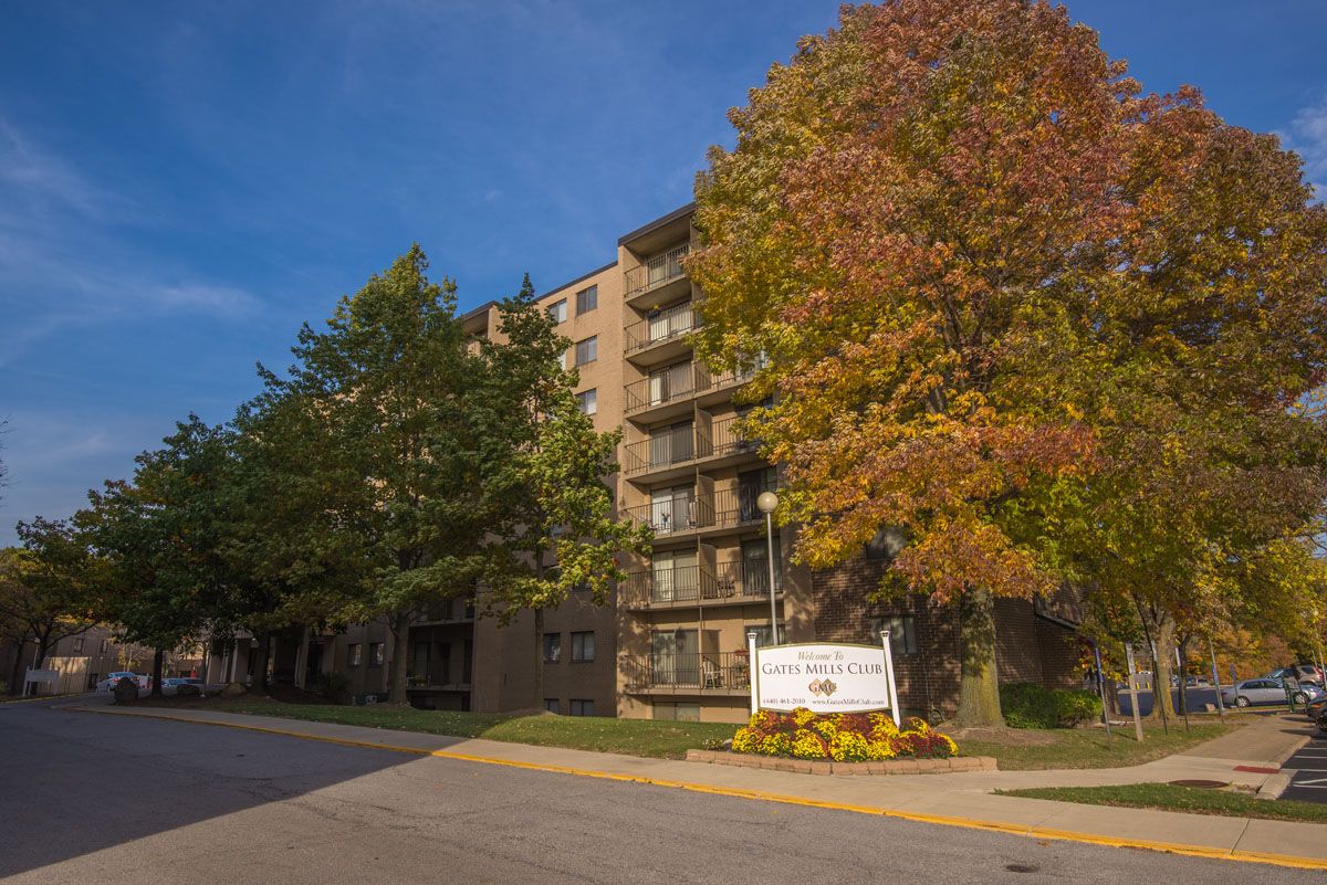 A residential apartment building surrounded by autumn trees with a sign in front.