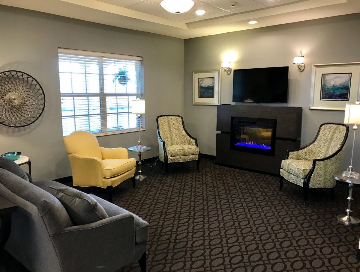 A cozy living room with comfortable chairs, a fireplace, and a mounted television.