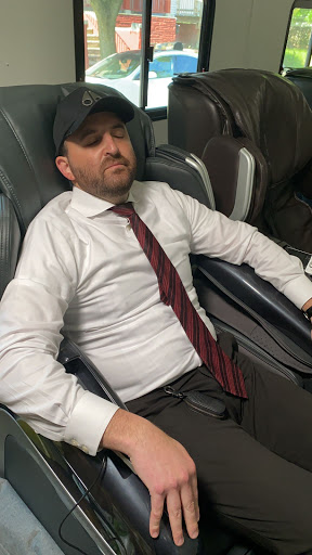 A man in business attire resting comfortably while seated.