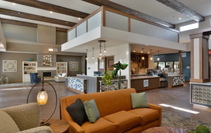 A modern open-concept living space featuring a cozy orange sofa, a spacious kitchen area, and contemporary decor.