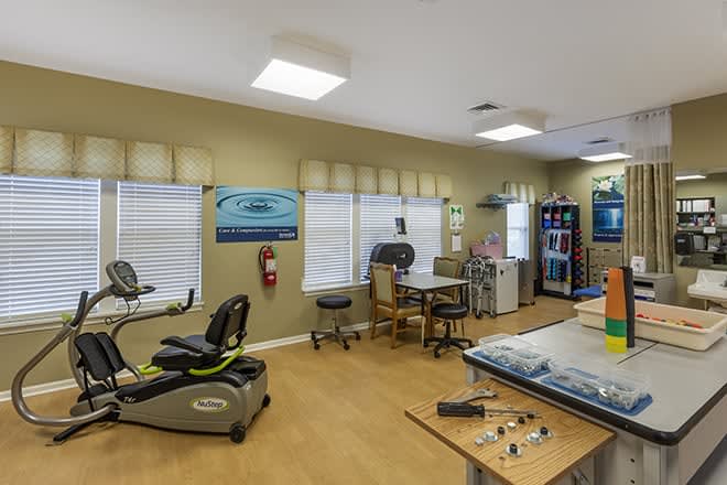 A physical therapy room equipped with exercise machines, tables, and medical equipment.