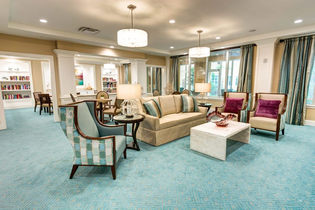A cozy and elegantly designed living room with comfortable seating, soft lighting, and a plush carpet.