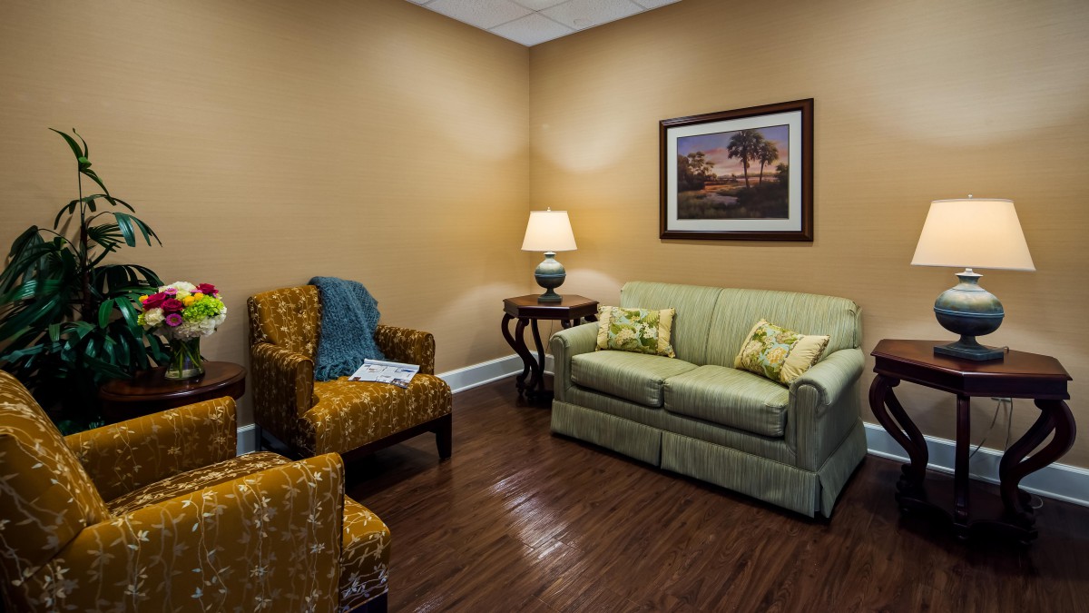 A cozy living room with a sofa, armchair, and a warm lamp.