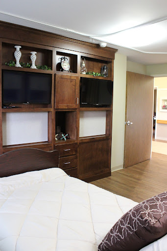 A cozy bedroom featuring wooden furniture, including cabinets with televisions and decorative items.