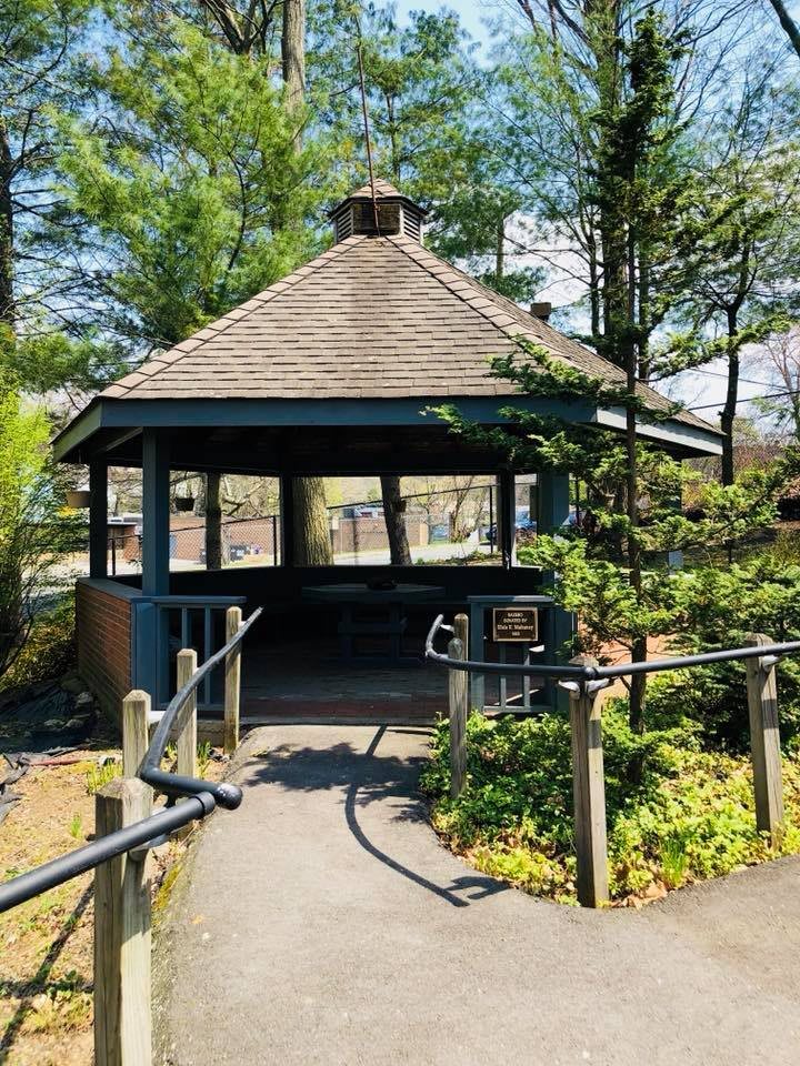 A peaceful gazebo surrounded by trees on a sunny day.