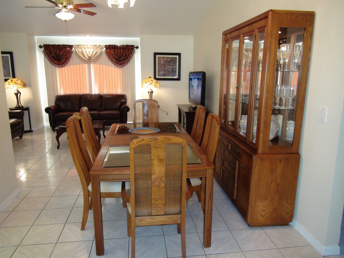 A dining area with wooden furniture and a cabinet, connecting to a living room.