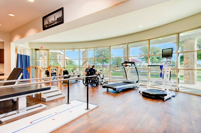 A modern gym with various exercise equipment and a view of the outdoors.