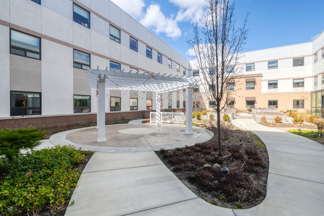 A modern building with a landscaped courtyard and a pathway leading to an outdoor structure.