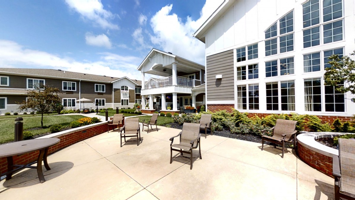 A sunny outdoor patio area with chairs and surrounding buildings.
