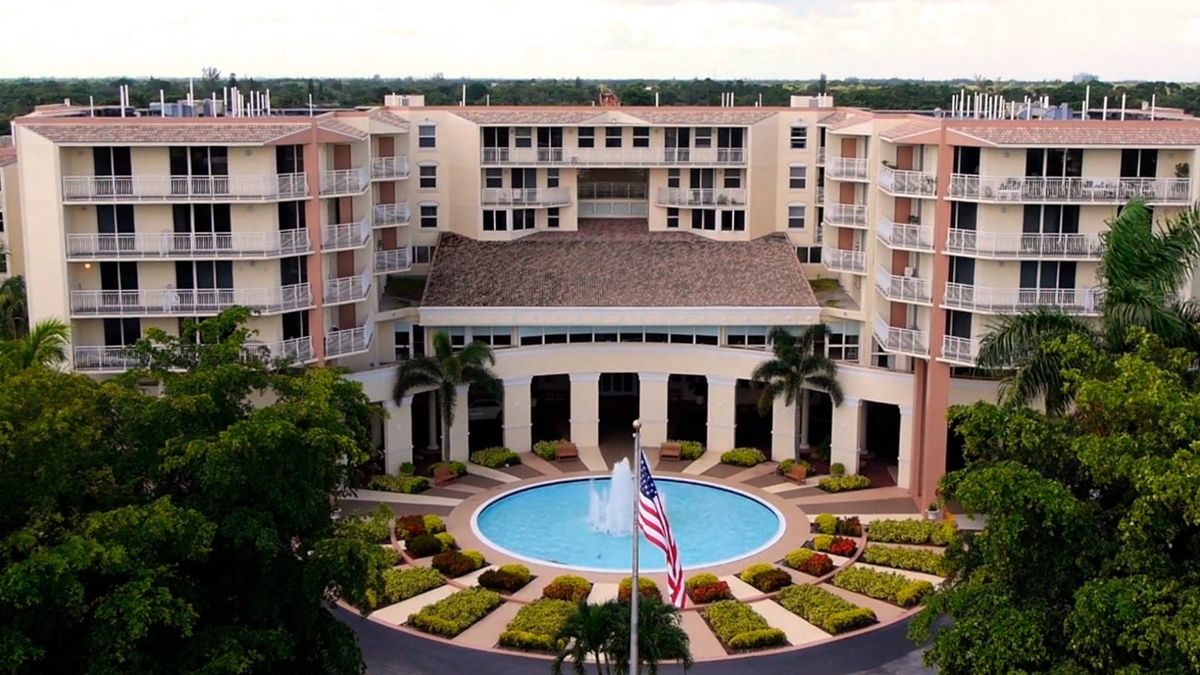 A view of a hotel with a central fountain and surrounding palm trees.