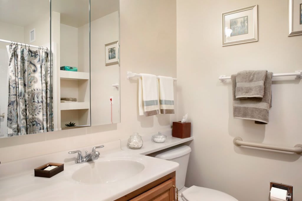 A neatly organized bathroom with a mirror, sink, and towels on display.