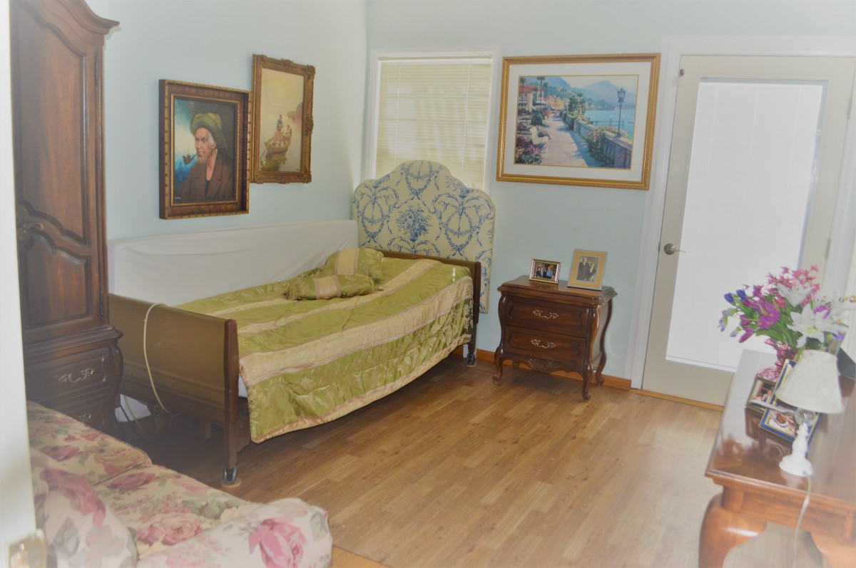 A cozy bedroom with a single bed, wooden floor, and decorative paintings on the wall.