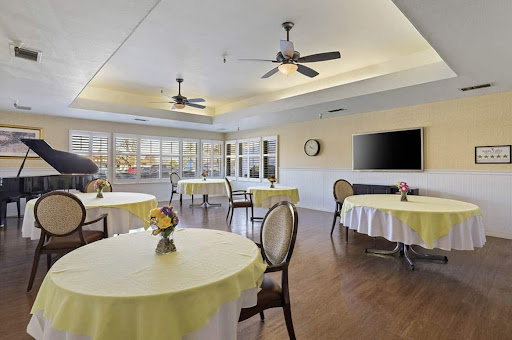 A bright and inviting dining area featuring tables with yellow tablecloths and ceiling fans, perfect for gatherings.