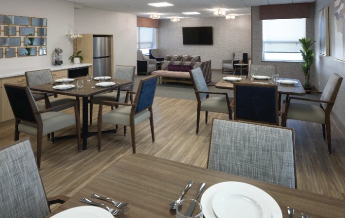 A modern dining area with neatly arranged tables and chairs, featuring wood flooring and a cozy atmosphere.