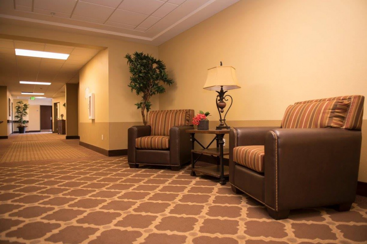 A cozy hallway features two armchairs, a side table with a lamp, and decorative elements including a potted plant.