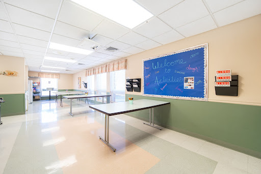 A spacious and empty classroom with tables and a blue board.