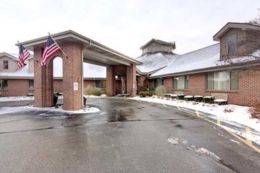 A building entrance with an American flag and snow on the ground.