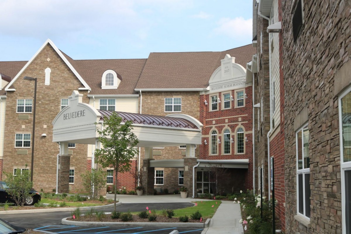 A view of a residential building with a covered entrance and landscaped surroundings.