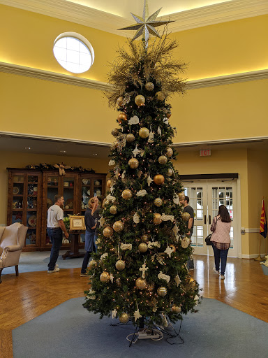 A beautifully decorated Christmas tree stands in a cozy interior, surrounded by people enjoying the festive atmosphere.