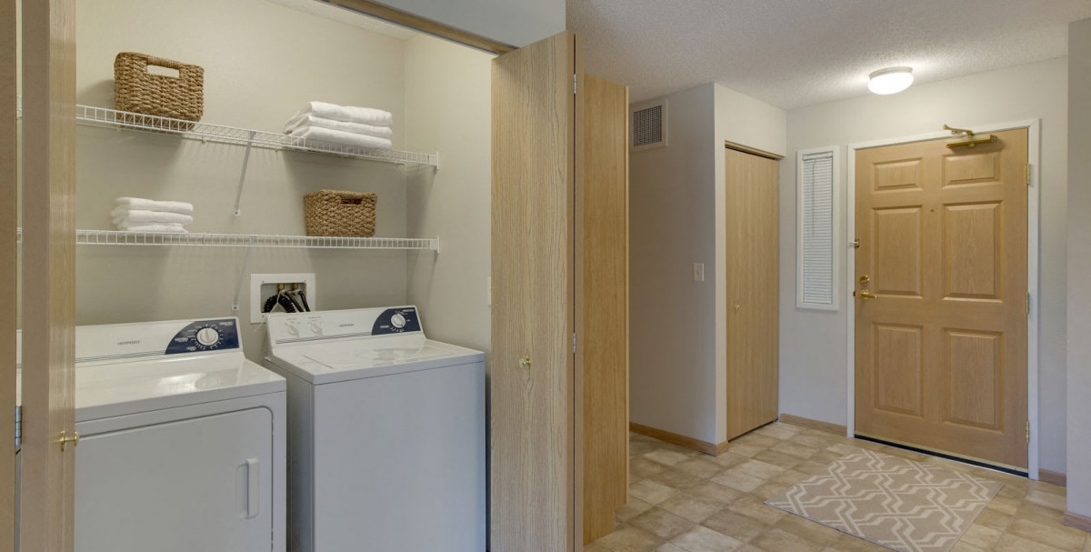 A laundry room featuring a washer and dryer with shelves above holding towels and a basket.