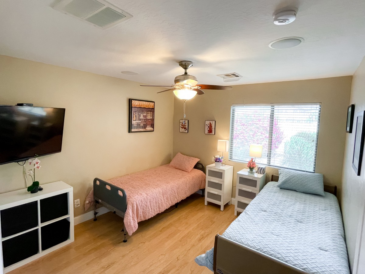 A cozy bedroom with two single beds, a ceiling fan, and natural lighting.